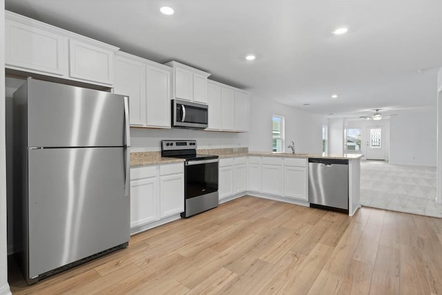 kitchen with appliances with stainless steel finishes, recessed lighting, light wood-style flooring, and white cabinets