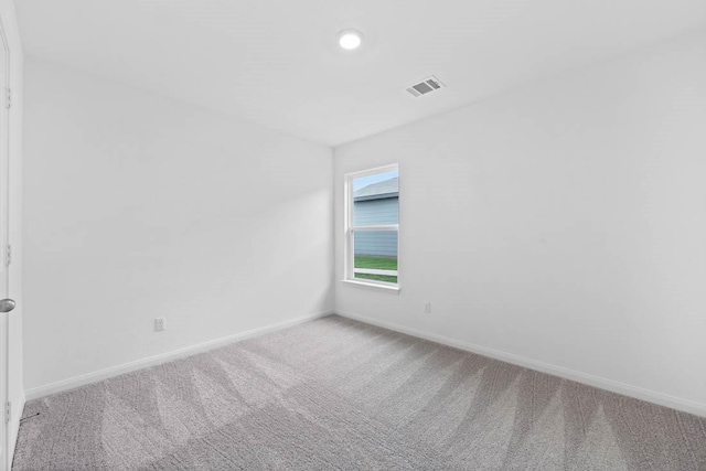 spare room featuring carpet, visible vents, and baseboards