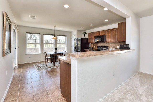 kitchen featuring brown cabinets, tasteful backsplash, light countertops, visible vents, and black appliances