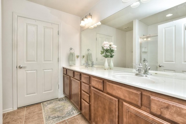 full bath with tile patterned floors, a sink, a shower stall, and double vanity