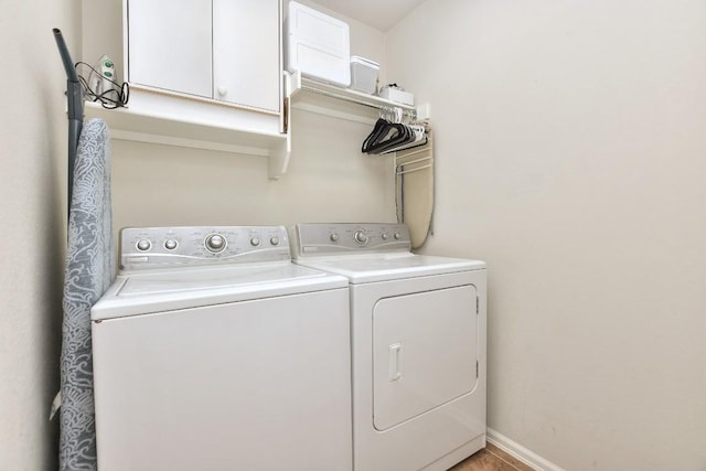 washroom featuring independent washer and dryer, cabinet space, and baseboards