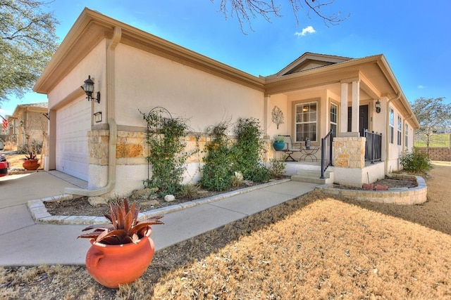 view of front facade featuring a garage, covered porch, and stucco siding