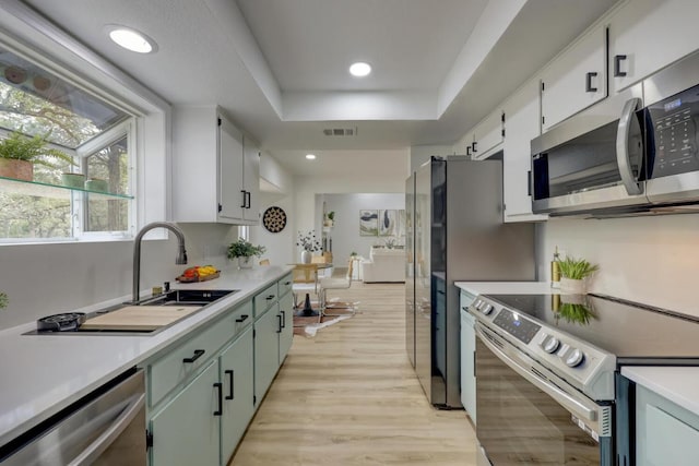 kitchen with stainless steel appliances, a sink, visible vents, light countertops, and a raised ceiling