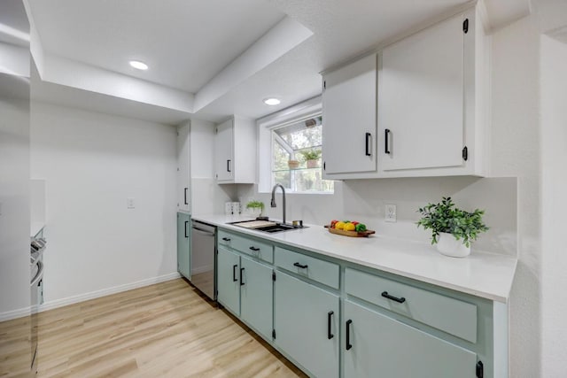 kitchen featuring baseboards, dishwasher, light wood-style flooring, light countertops, and a sink