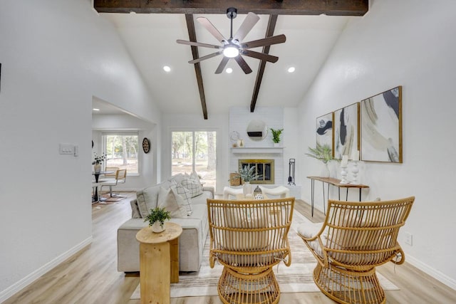 living area featuring beamed ceiling, a fireplace, and light wood-style floors