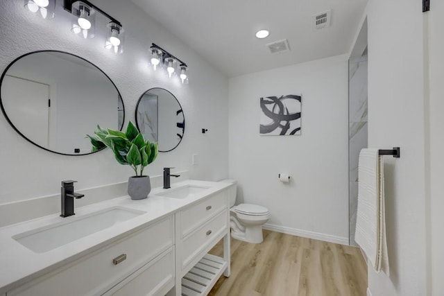 bathroom with visible vents, a sink, toilet, and wood finished floors