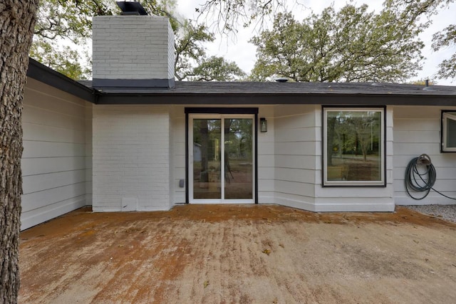 back of house featuring brick siding and a chimney