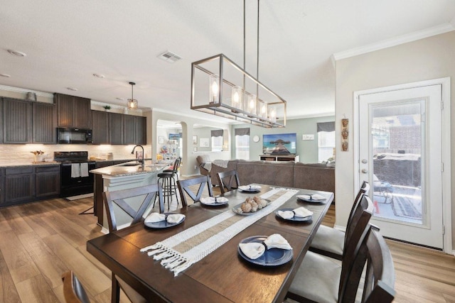 dining area featuring light wood-type flooring, visible vents, and crown molding