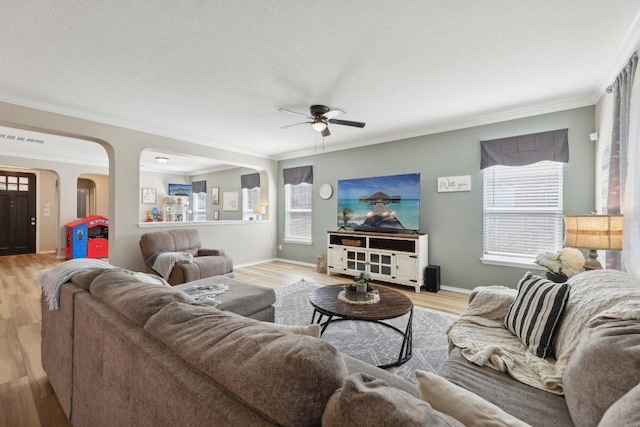 living room featuring visible vents, arched walkways, ornamental molding, wood finished floors, and a textured ceiling