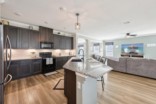 kitchen with black appliances, visible vents, a kitchen breakfast bar, and a sink