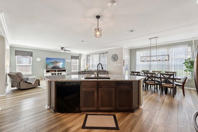 kitchen featuring black dishwasher, a center island with sink, light wood-style flooring, open floor plan, and a sink