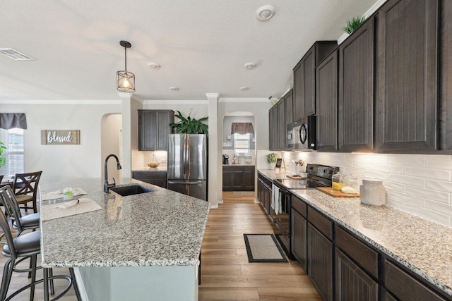 kitchen with tasteful backsplash, visible vents, arched walkways, black appliances, and a sink