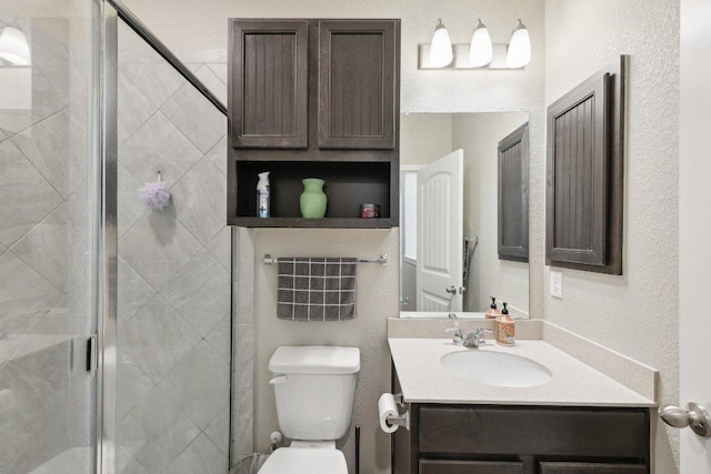 full bath featuring a stall shower, a textured wall, vanity, and toilet