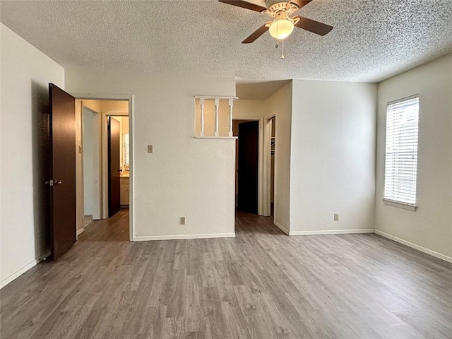 spare room with a textured ceiling, baseboards, and wood finished floors