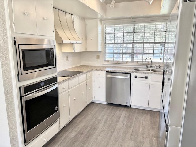 kitchen featuring a sink, light countertops, appliances with stainless steel finishes, light wood-type flooring, and custom exhaust hood