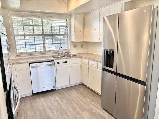 kitchen with light wood finished floors, appliances with stainless steel finishes, light countertops, and a sink