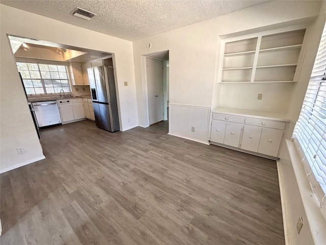 kitchen featuring a textured ceiling, stainless steel appliances, visible vents, white cabinetry, and dark wood-style floors