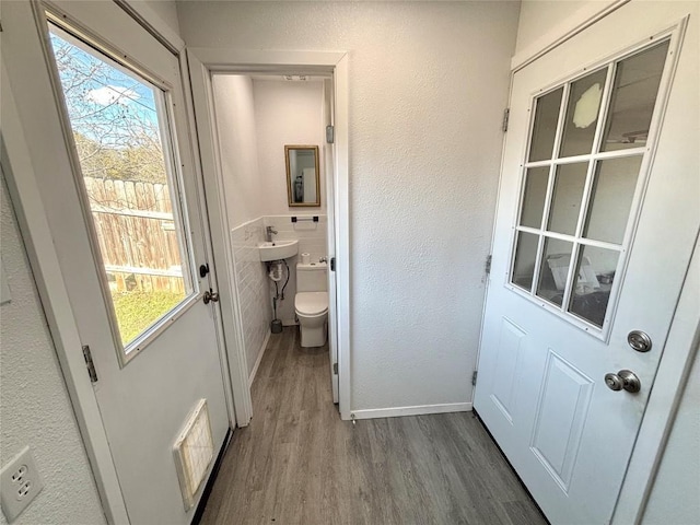 entryway featuring a textured wall, wood finished floors, visible vents, and baseboards