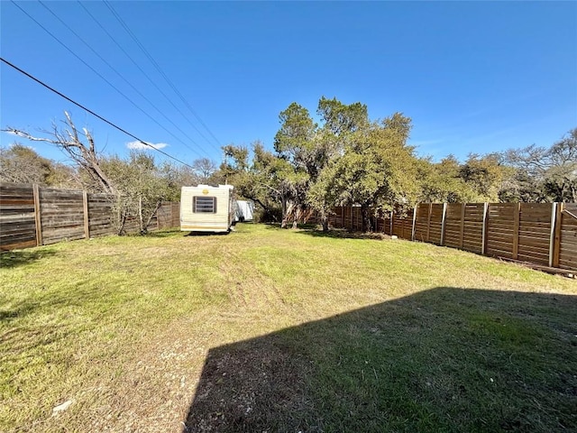 view of yard with a fenced backyard, a storage unit, and an outbuilding