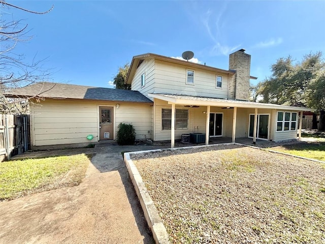 back of property with ceiling fan, a chimney, a patio area, and fence