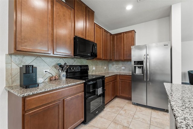 kitchen with black appliances, tasteful backsplash, light tile patterned floors, and light stone counters