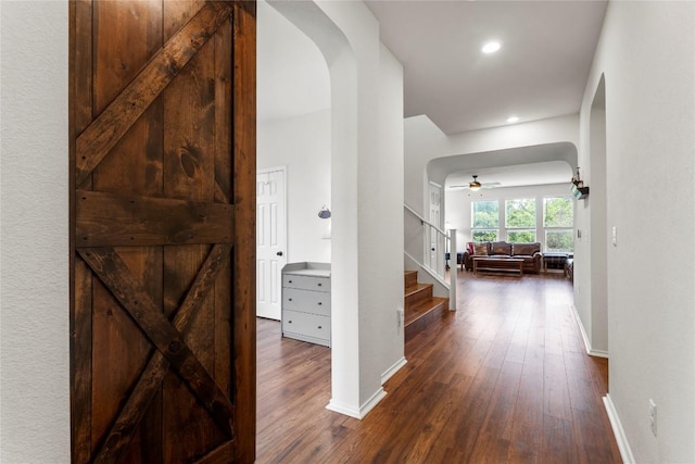 hallway with arched walkways, recessed lighting, dark wood-type flooring, baseboards, and stairway