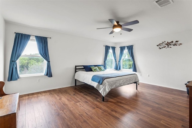 bedroom featuring ceiling fan, wood finished floors, visible vents, and baseboards