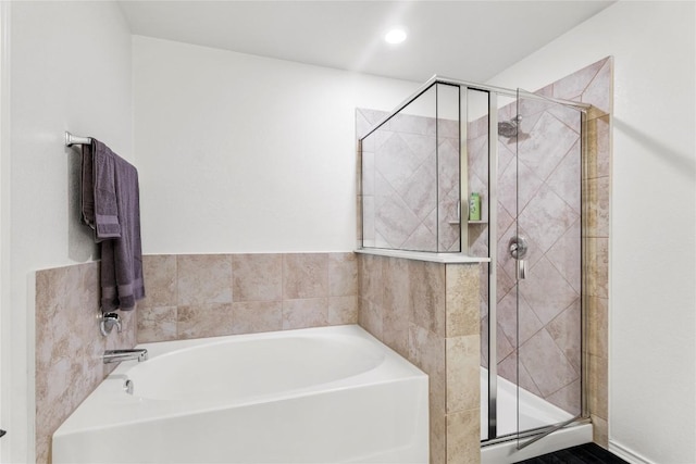 bathroom featuring a shower stall and a bath