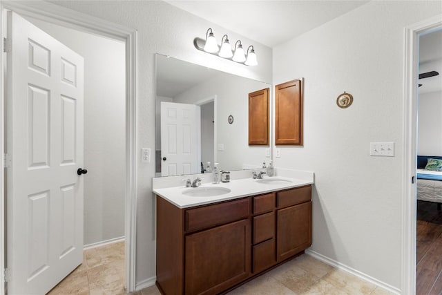 full bath with double vanity, a sink, baseboards, and ensuite bathroom