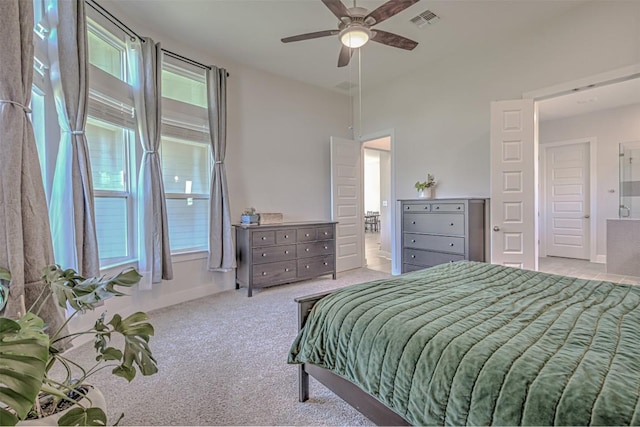 carpeted bedroom featuring baseboards, ensuite bath, visible vents, and a ceiling fan