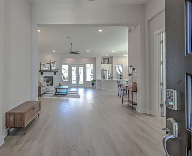 entrance foyer featuring light wood-style floors, recessed lighting, baseboards, and a glass covered fireplace