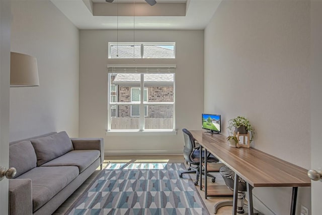 office area with a ceiling fan and a raised ceiling