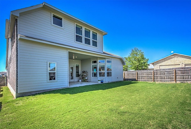 rear view of property with a fenced backyard, a lawn, and a patio