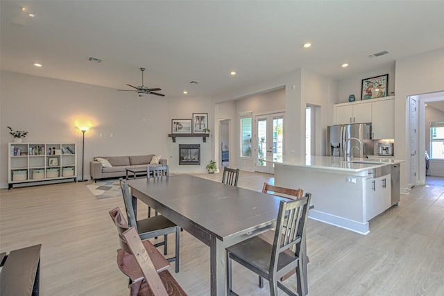 dining area with a glass covered fireplace, french doors, visible vents, and a healthy amount of sunlight