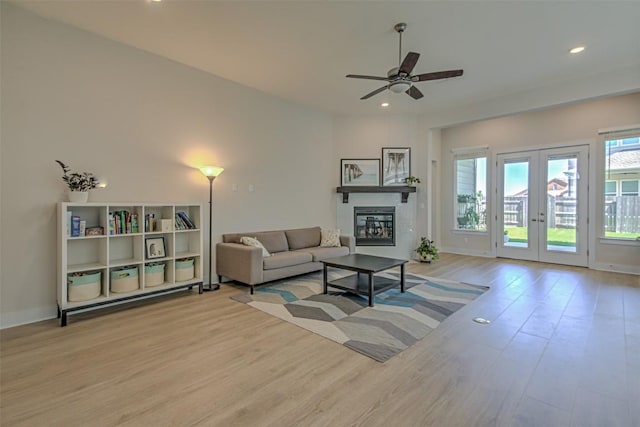 living area featuring recessed lighting, wood finished floors, baseboards, french doors, and a glass covered fireplace