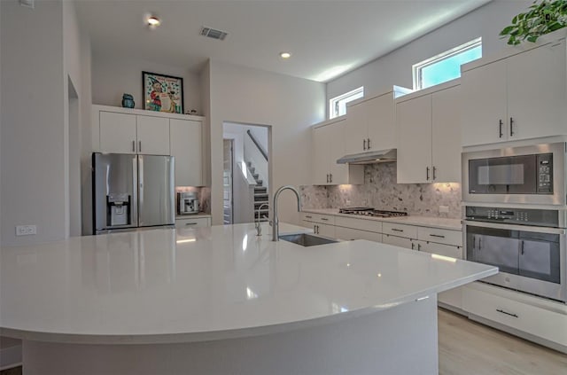 kitchen featuring tasteful backsplash, visible vents, appliances with stainless steel finishes, light countertops, and under cabinet range hood