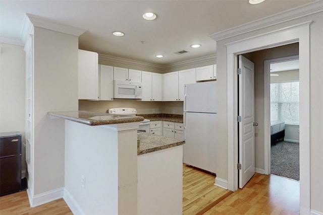 kitchen featuring ornamental molding, white appliances, visible vents, and a peninsula