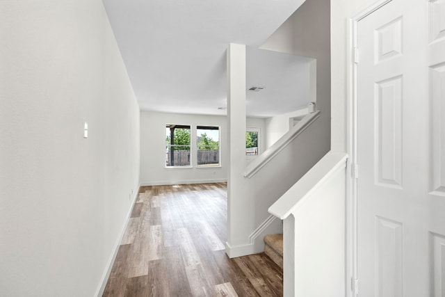 corridor with stairs, wood finished floors, visible vents, and baseboards