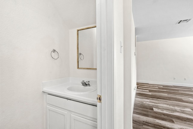 bathroom featuring visible vents, vanity, baseboards, and wood finished floors