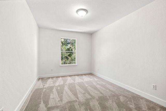 carpeted empty room featuring baseboards