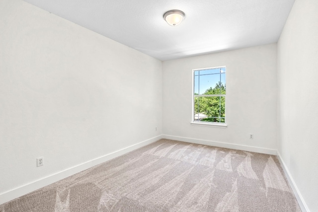 unfurnished room with baseboards and light colored carpet