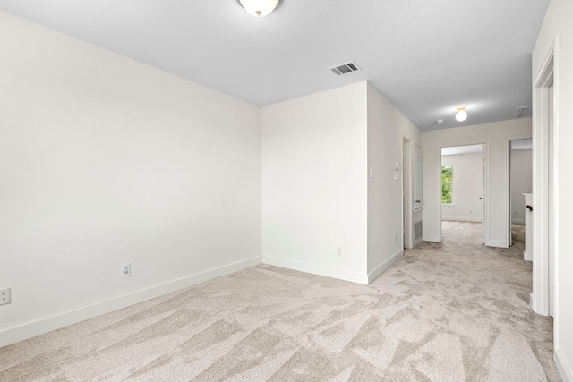 unfurnished room featuring light carpet, visible vents, and baseboards