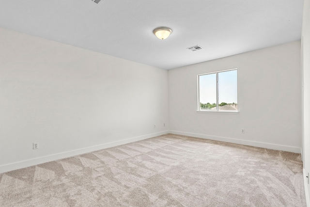 spare room featuring light carpet, visible vents, and baseboards