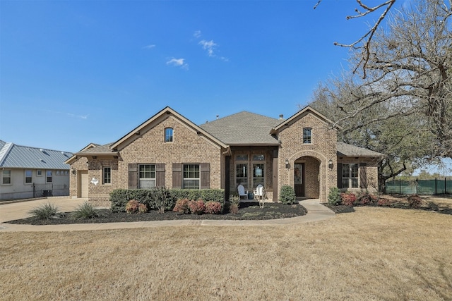 view of front of house with an attached garage, brick siding, fence, and a front lawn