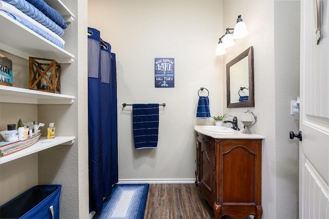 bathroom with baseboards, wood finished floors, and vanity