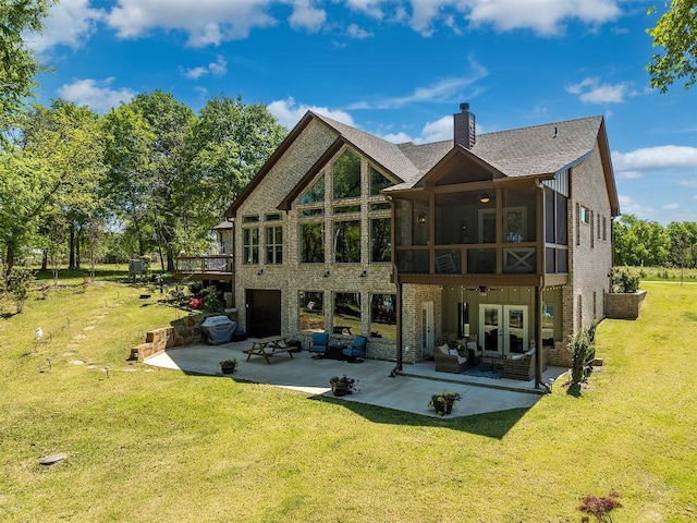 rear view of house featuring a sunroom, french doors, a lawn, a chimney, and a patio area