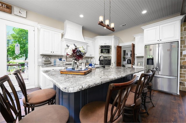 kitchen featuring a breakfast bar area, white cabinetry, appliances with stainless steel finishes, decorative backsplash, and dark wood-style floors