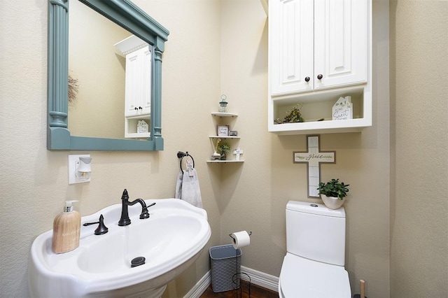 bathroom with baseboards, a sink, and toilet