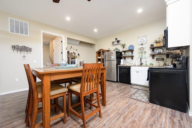 kitchen featuring open shelves, visible vents, white cabinets, light wood-type flooring, and black appliances