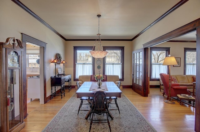 dining room featuring light wood-type flooring, crown molding, and baseboards